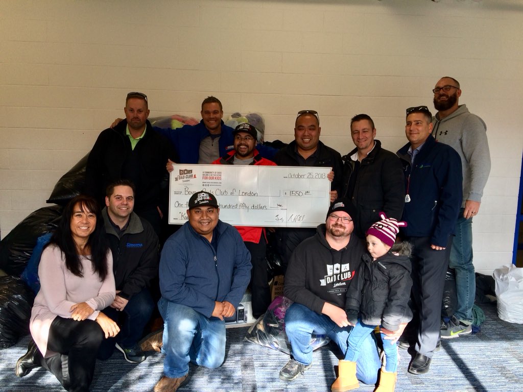 Volunteers with the Boys and Girls Club of London and the Dad Club of London pose in front of donated coats on October 25, 2018.