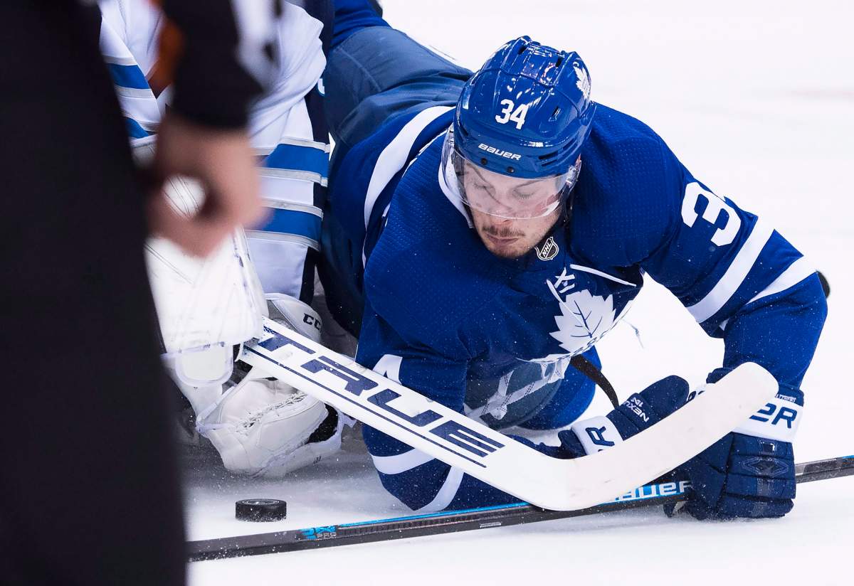 Toronto Maple Leafs centre Auston Matthews (34) battles for the loose puck with Winnipeg Jets goaltender Connor Hellebuyck (37) during first-period NHL hockey action in Toronto on Saturday, Oct. 27, 2018.