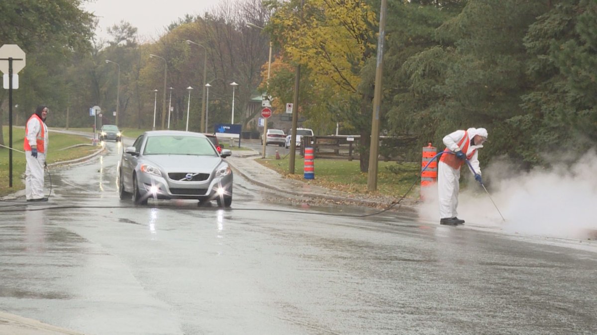 Cars drive through on Camillien Houde Way and Remembrance Road, as workers wash away markings associated with the temporary closure over the summer.  The street was re-opened hours before.  (Global News).