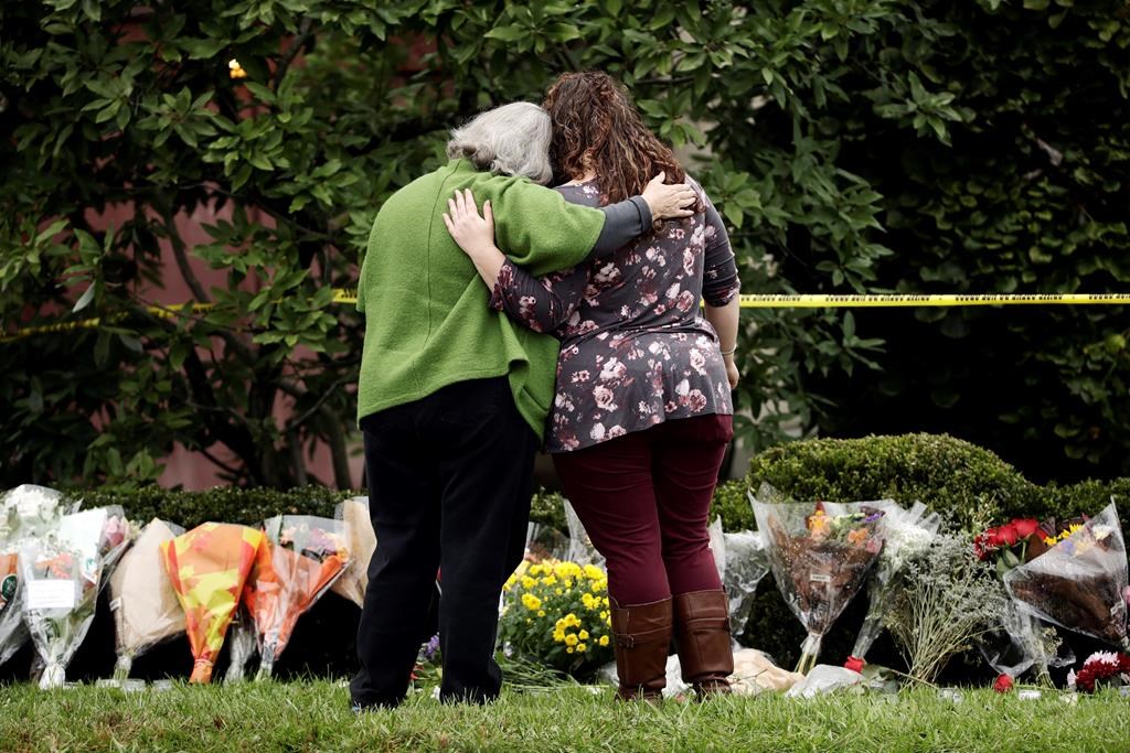 Two people support each other in front of flowers at a makeshift memorial at the Tree of Life Synagogue in Pittsburgh, Sunday, Oct. 28, 2018. Robert Bowers, the suspect in Saturday's mass shooting at the synagogue, expressed hatred of Jews during the rampage and told officers afterward that Jews were committing genocide and he wanted them all to die, according to charging documents made public Sunday. THE CANADIAN PRESS/AP-Matt Rourke.