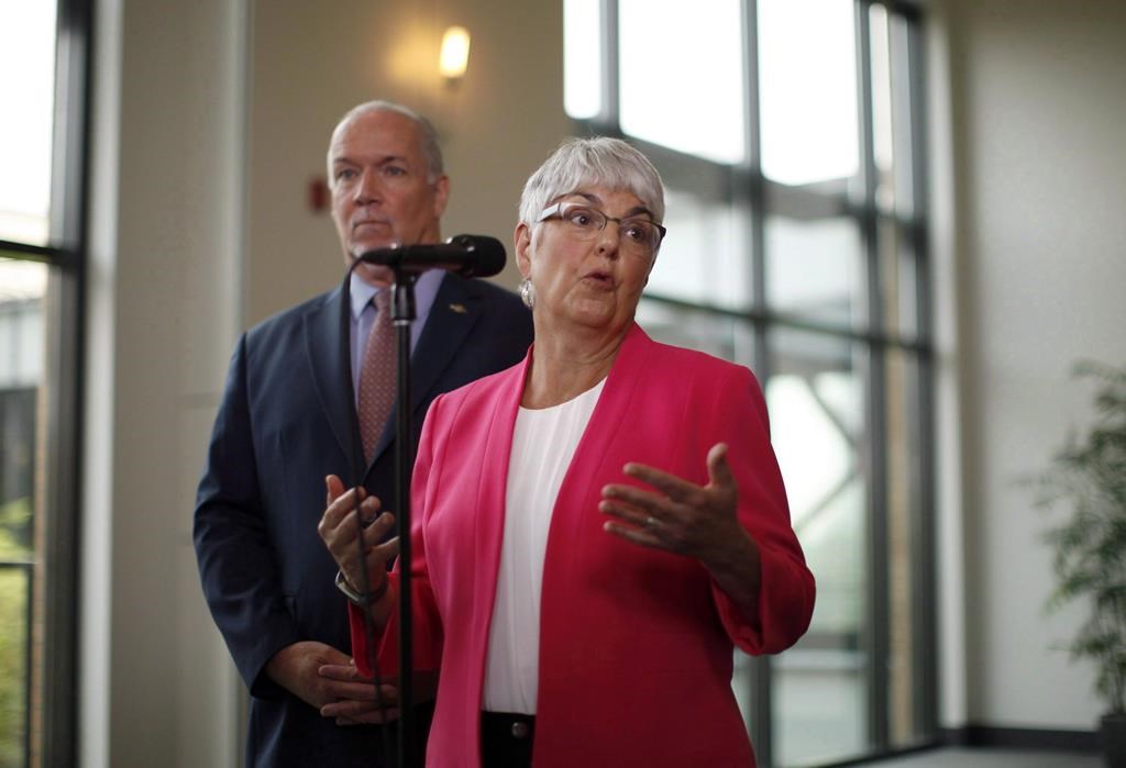 B.C. Premier John Horgan looks on as MLA Carole James answers a question during a media scrum following a meeting with federal ministers at the Vancouver Island Conference Centre during day two of the Liberal cabinet retreat in Nanaimo, B.C., on August 22, 2018. The British Columbia government has introduced a speculation and vacancy tax that Finance Minister Carole James says will moderate the overheated housing market and create more homes for renters.James says the aim of the tax is to improve housing affordability for thousands of people, including seniors forced to live in their vehicles and young professionals who leave the province because they can't find a place to live. THE CANADIAN PRESS/Chad Hipolito.