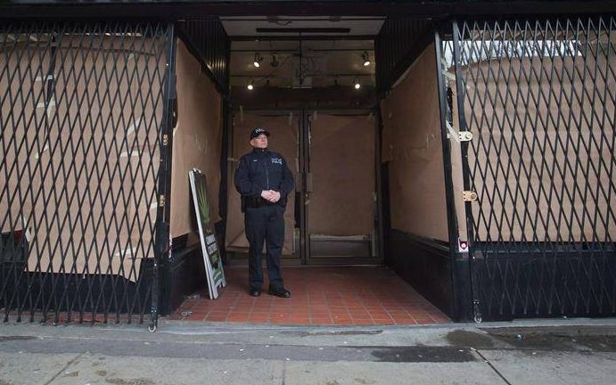 A police officer stands outside a pot shop during a police raid, in Vancouver, B.C., on Thursday March 9, 2017. More than two dozen more stores are being forced to close in Vancouver following a B.C. Supreme Court ruling Thursday.
