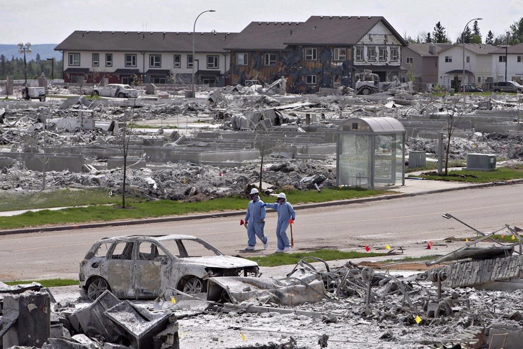 Workers put out markers around a devastated area of Timberlea in Fort McMurray Alta, on Thursday, June 2, 2016. Newly published research suggests the fire cast a lasting shadow over the lives of many residents who are still experiencing elevated rates of depression and related mental-health problems.