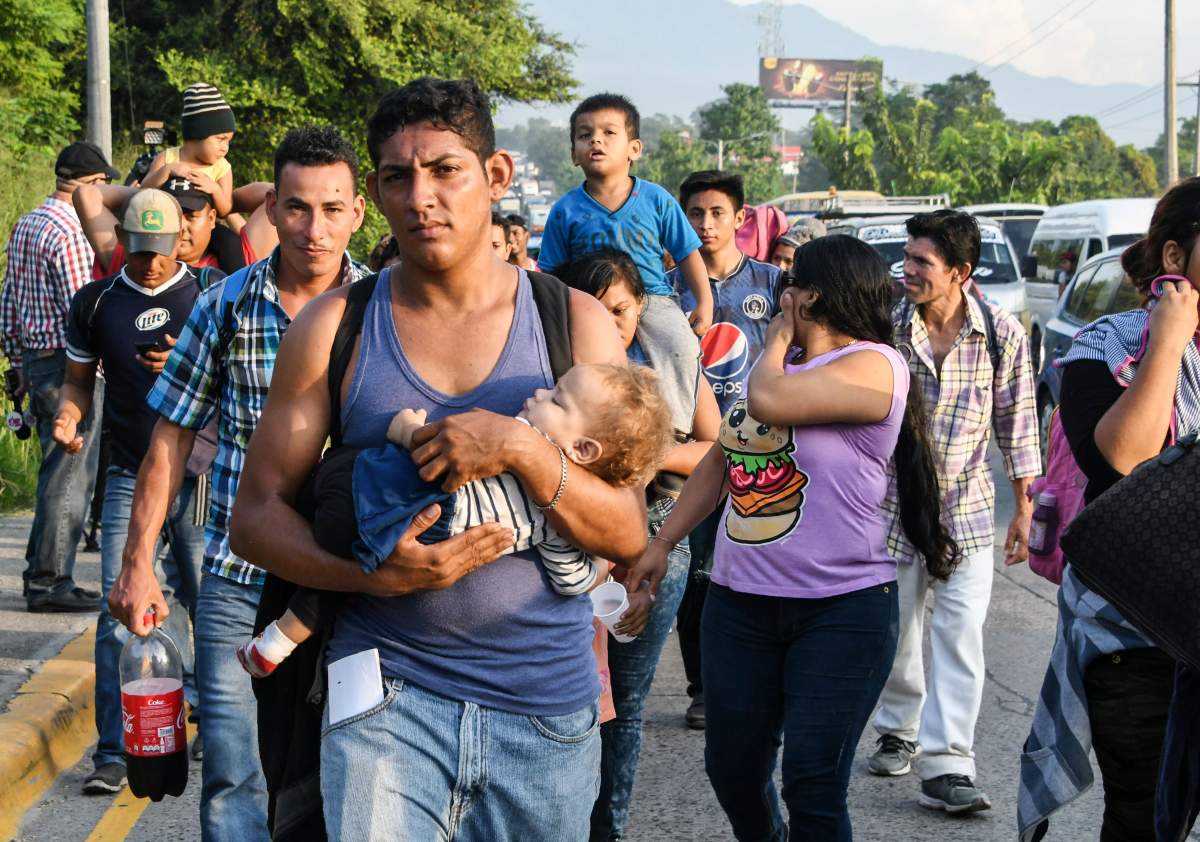 A Honduran man carries a child in his arms during an exodus towards the U.S. from San Pedro Sula.