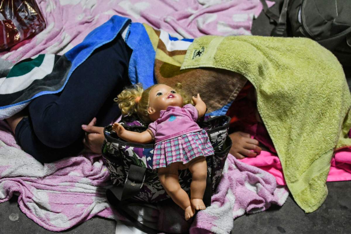 A Honduran girl sleeps with her family in the bus station of San Pedro Sula, the night before the exodus towards U.S. began, on October 13, 2018. –