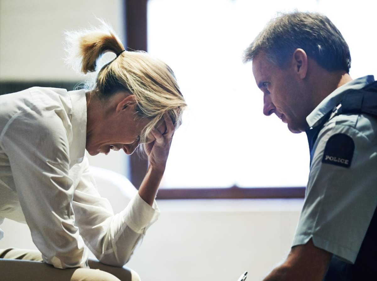 Shot of a grief stricken woman giving her statement to a police officer at a crime scene
.