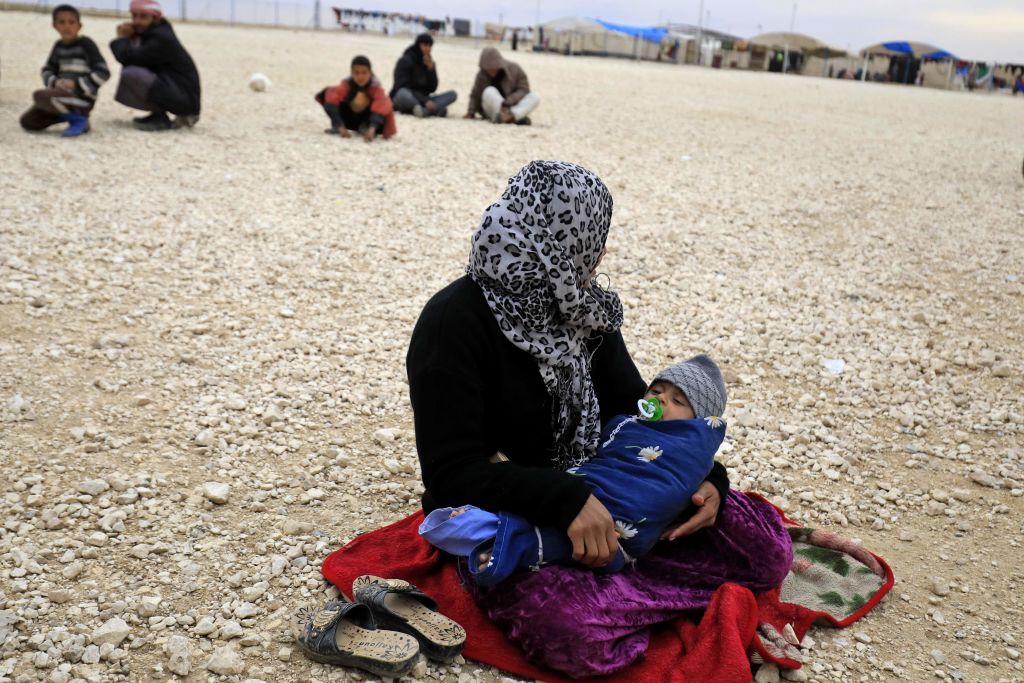 A displaced Syrian sits holding her child at a refugee camp in northeastern Syria, Feb. 26, 2018. 
DELIL SOULEIMAN/AFP/Getty Images).