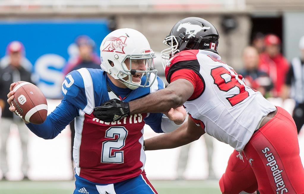 Montreal Alouettes quarterback Johnny Manziel, left, evades a tackle by Calgary Stampeders' Ja'Gared Davis during first half CFL football action in Montreal, Monday, October 8, 2018.