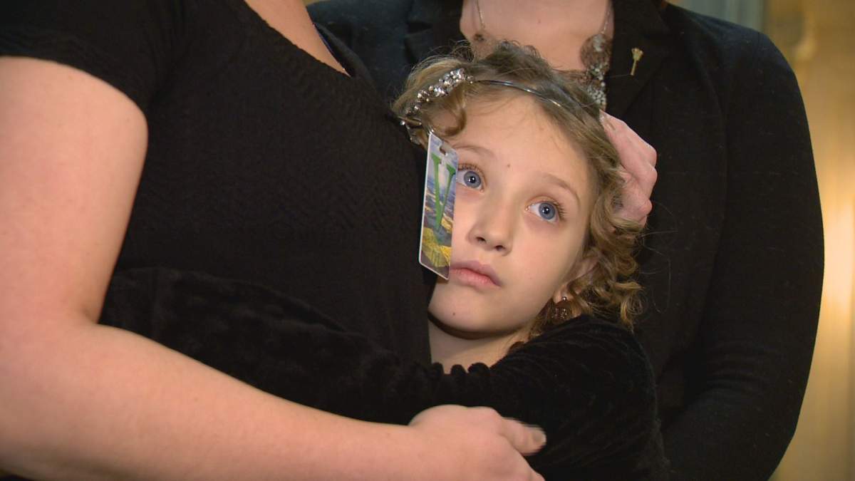 Gracie Prang hugs her mom, Stephanie Schneck, while she talks to the media at Saskatchewan's legislative assembly. 