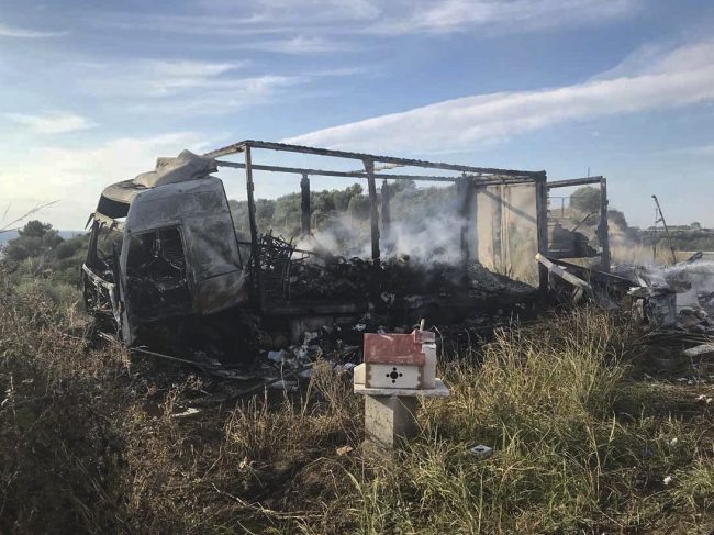 A burn-out truck on a field behind a small chapel, next to a motorway, following a collision near Greece's northern town of Kavala, Oct. 13, 2018. 
