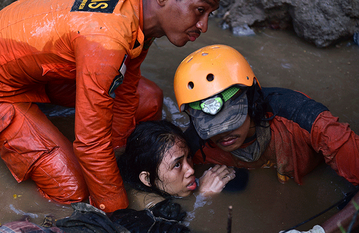 Rescuers evacuate an earthquake survivor by a damaged home following earthquakes and tsunami in Palu, Central Sulawesi, Indonesia, Sept. 30, 2018.