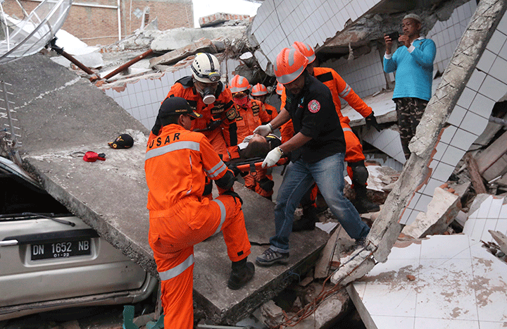 Rescuers carry an earthquake survivor from a building damaged in Palu, Central Sulawesi, Indonesia, Sept. 30, 2018.