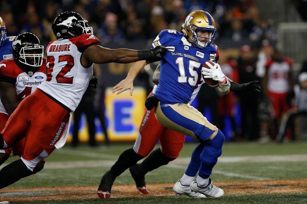 Winnipeg Blue Bombers quarterback Matt Nichols (15) attempts to get out of the grasp of Calgary Stampeders' Ese Mrabure (92) during the first half of CFL action in Winnipeg, Friday, Oct. 26, 2018.