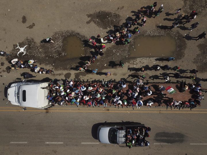 Migrants climb on the trailer of a truck as others wait in a line for a ride on the road that connects Tapanatepec with Niltepec, Mexico, as a caravan of Central Americans continues its slow march toward the U.S. border, Monday, Oct. 29, 2018.