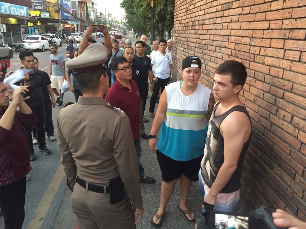 In this Thursday, Oct. 18, 2018, photo, British Furlong Lee, right, and Canadian Brittney Lorretta Katherine Schneider, second right, stand in front of Tha Pae Gate in Chiang Mai province, northern Bangkok, Thailand. (Chiang Mai News via AP).