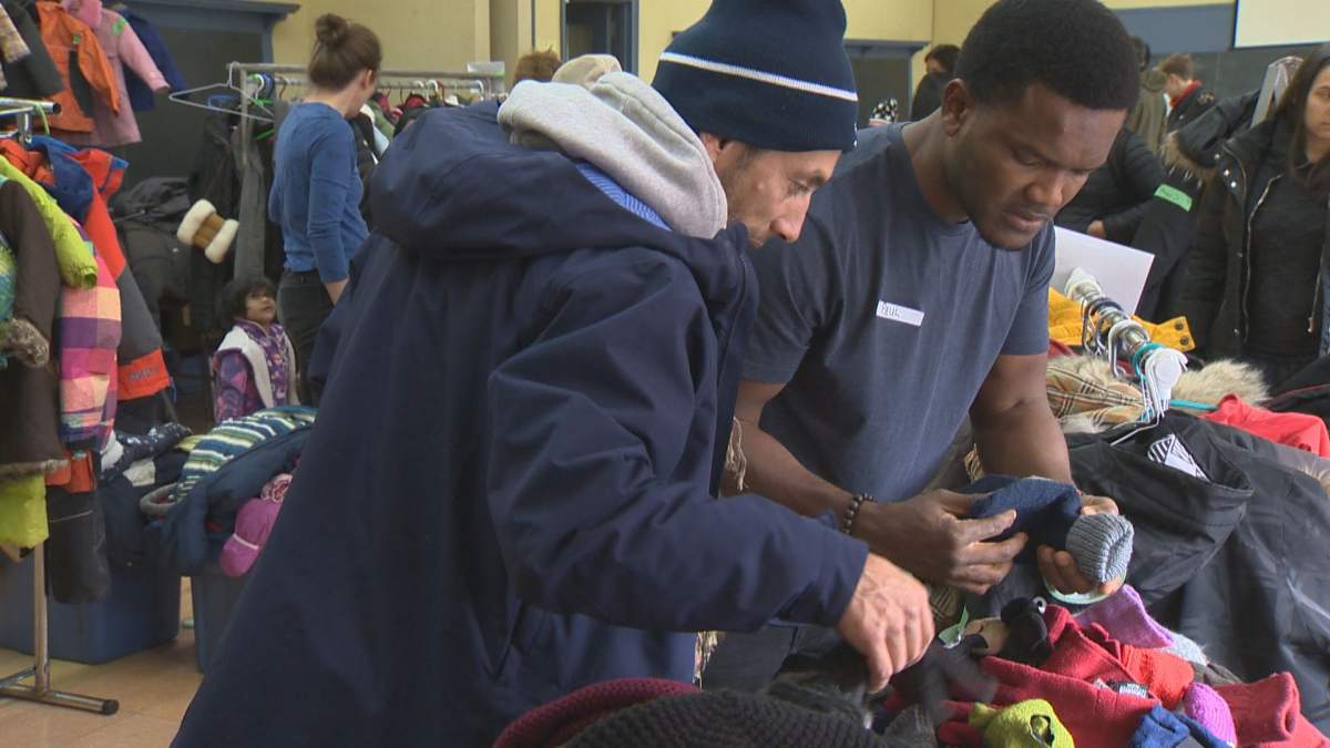 A volunteer helps an asylum seeker at the winter clothing drive in Villeray on Saturday, Oct. 27, 2018.