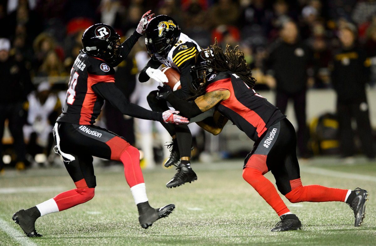 Hamilton Tiger-Cats wide receiver Brandon Banks (16) gets tackled by Ottawa Redblacks defensive backs Devin Butler (14) and Rico Murray (3) during second half CFL action in Ottawa on Friday, Oct. 19, 2018.