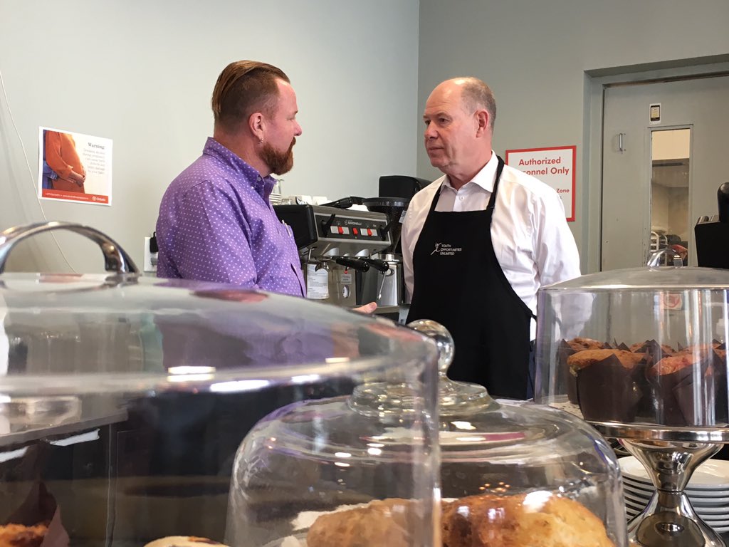 Jeff Macoun, (left) learns from Mark Beacock, food and beverage team leader at the YOU Cafe, before serving people coffee and lunch ahead of the funding announcement.