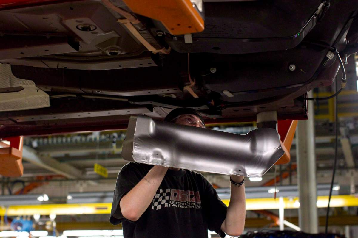 An assembly line worker at the General Motors Assembly plant in Oshawa works on a car on Friday December 16, 2011. General Motors and the Canadian auto workers union Unifor have reached a tentative contract agreement, averting a strike that was threatened for midnight Monday.
