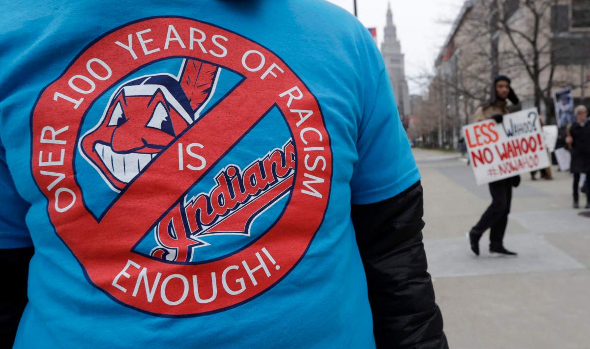 A man wears a shirt in protest of Chief Wahoo before a home opener baseball game between the Kansas City Royals and the Cleveland Indians, Friday, April 6, 2018, in Cleveland.