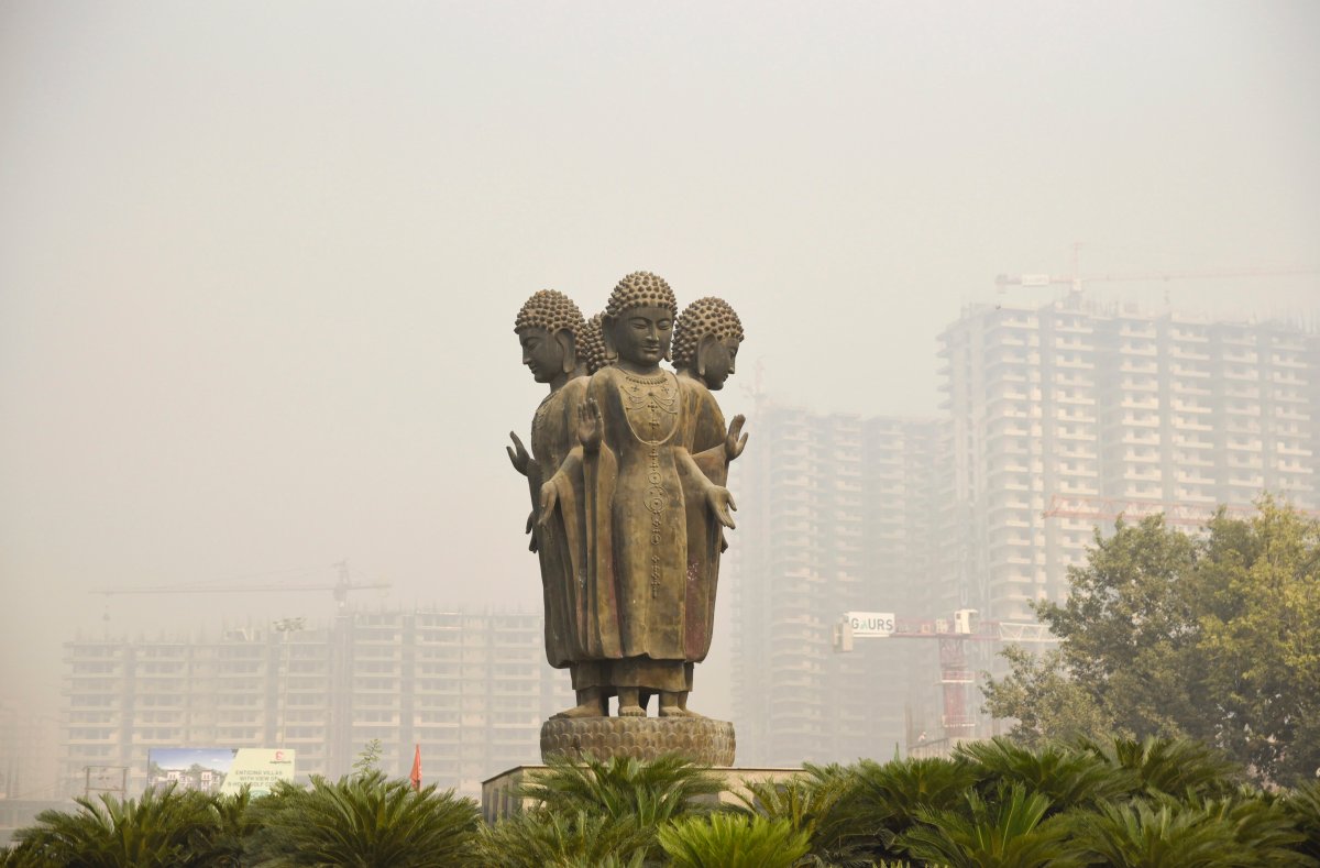 Highrise residential buildings under construction are partly visible behind a Buddha statue due to smog in Greater Noida, near New Delhi, India, Friday, Oct. 26, 2018. 