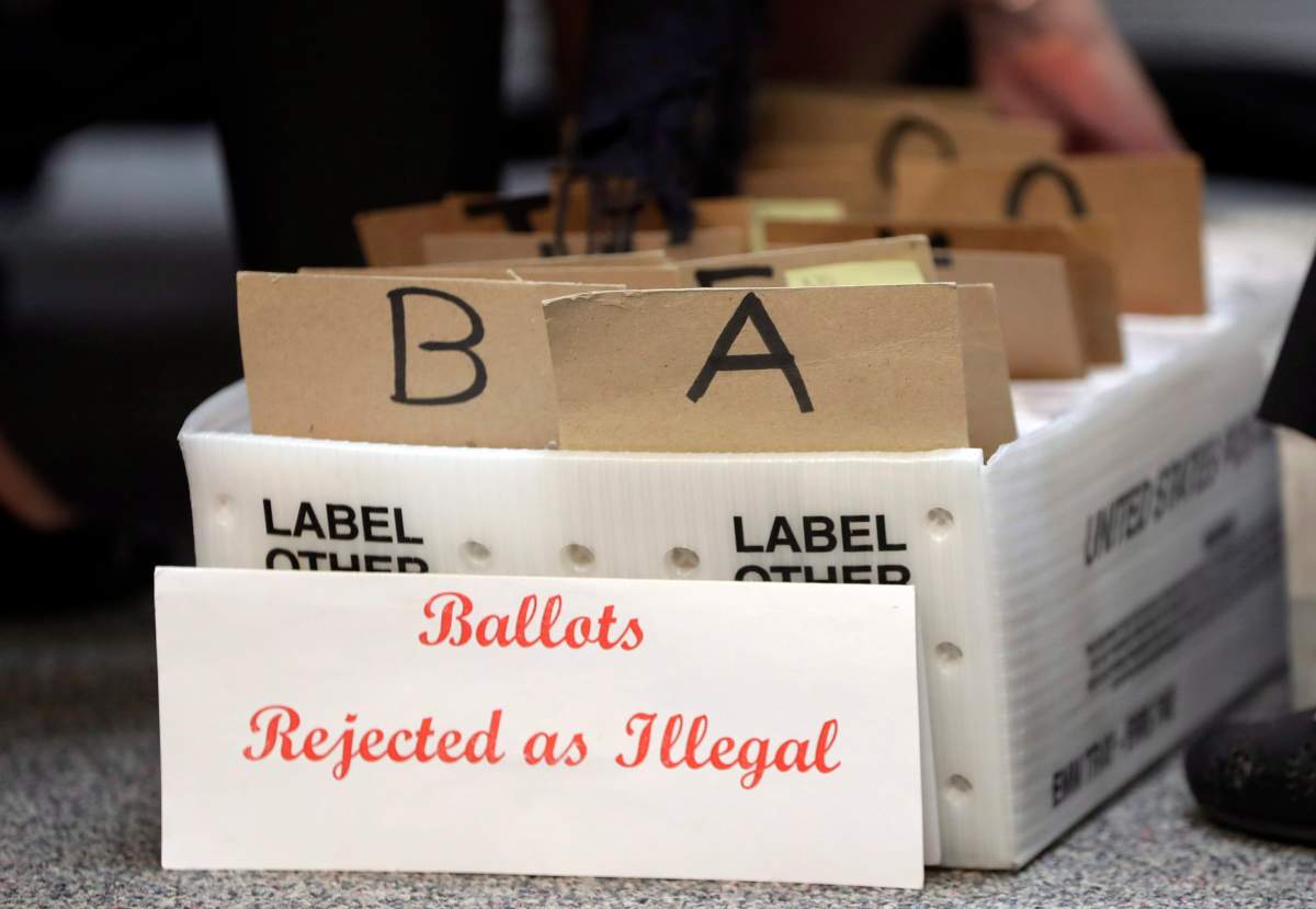 In this Tuesday, Oct. 30, file photo, rejected mail-in ballots sit in a box as members of the canvassing board verify signatures on the ballots at the Miami-Dade County Elections Department, in Miami, Fla. 