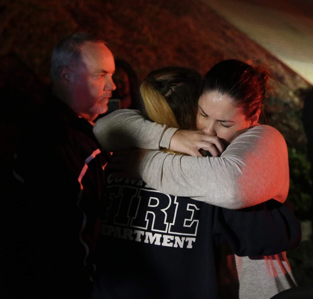 A woman who fled the Borderline Bar and Grill where a gunman injured 11 people is hugged by relatives in Thousand Oaks.