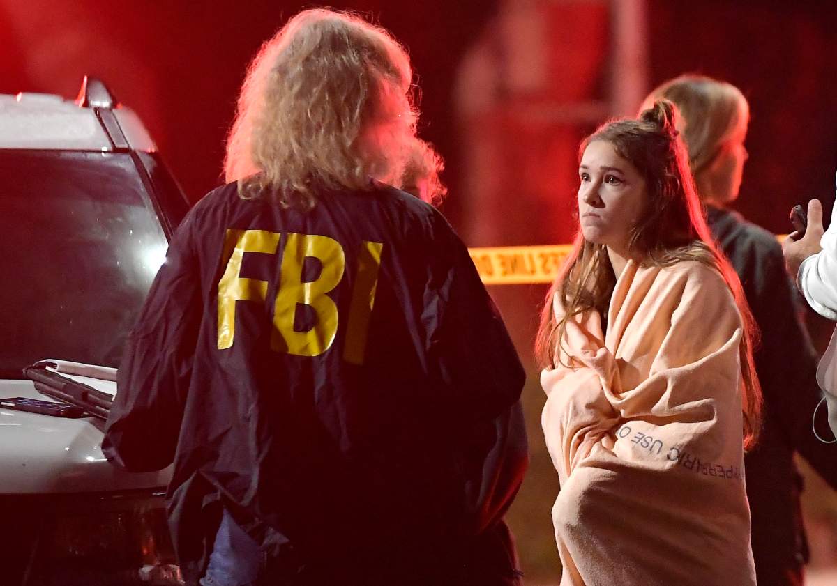 An FBI agent talks to a potential witness as they stand near the scene Thursday, Nov. 8, 2018, in Thousand Oaks, Calif.