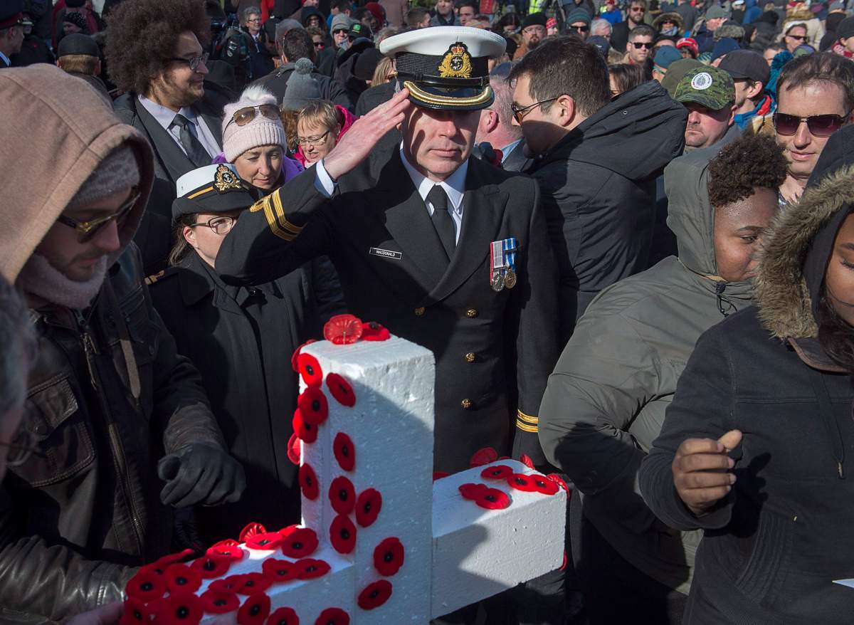 A member of the Royal Canadian Navy salutes after placing his poppy on a cross during Remembrance Day ceremonies at the Grand Parade in Halifax on Sunday, Nov. 11, 2018.