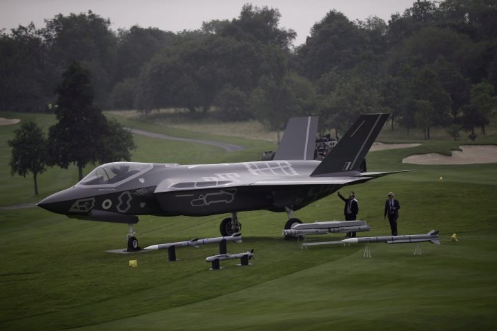 Men look at a demonstration F35 jet standing on display beside a golf course prior to a NATO summit at the Celtic Manor Resort in Newport, Wales, Wednesday, Sept. 3, 2014.