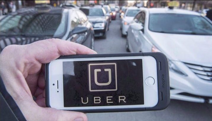 The Uber logo is seen in front of protesting taxi drivers at the courthouse in Montreal, Tuesday, Feb. 2, 2016. 
