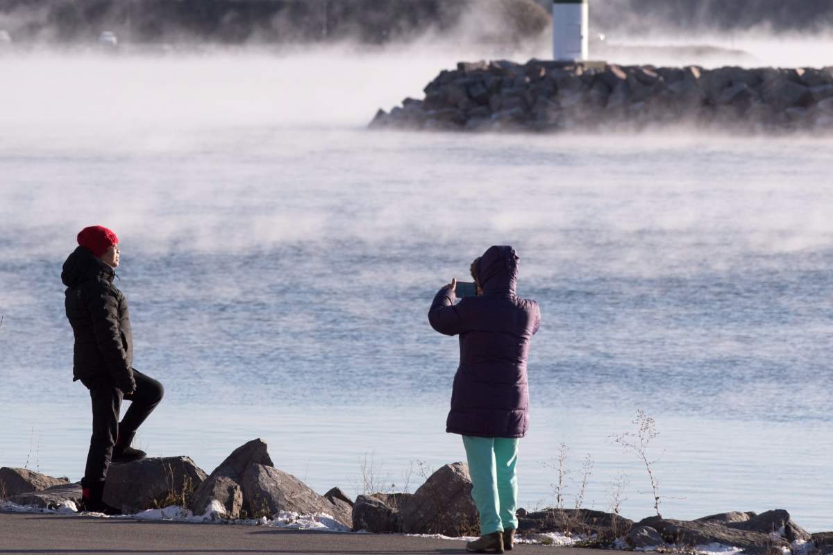 People take picture as mist rises from Lake Ontario during a winter cold snap in the area in Kingston, Ont. on Thursday, Nov. 22, 2018. 