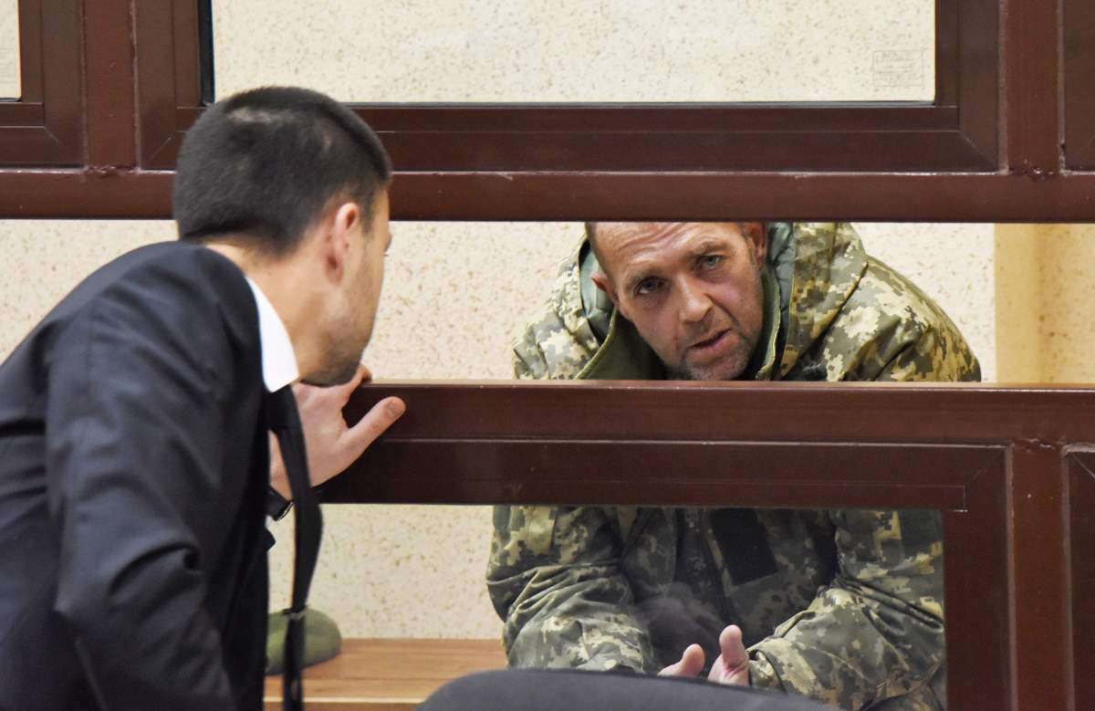 One of the captured Ukrainian sailors speaks with his lawyer in a court room in Simferopol, Crimea, Tuesday, Nov. 27, 2018. A Crimean court has ordered one of the Ukrainian seamen captured by Russia at the weekend held in custody for the next two months. The seamen and their vessels were captured by Russian border guards late on Sunday as they were about to make their way through the Kerch Strait near Crimea.