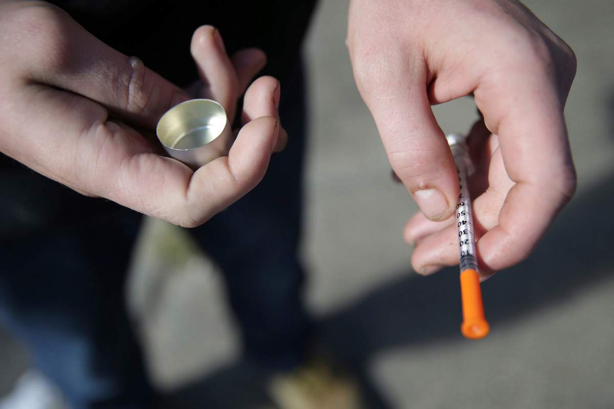 In this Oct. 22, 2018 file photo, a fentanyl user holds a needle near Kensington and Cambria in Philadelphia. Suicides and drug overdoses helped lead a surge in U.S. deaths last year, and drove a continuing decline in how long Americans are expected to live. 