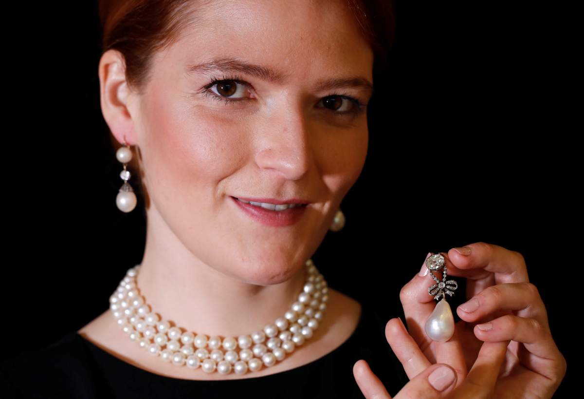 A model holds a natural pearl and diamond pendant once owned by Marie Antoinette together with wearing a pair of natural drops and a necklace featuring 119 natural pearls during a press preview ahead of the upcoming auction “Royal jewels from the Bourbon Parma Family” at Sotheby’s in Geneva November 7, 2018. REUTERS/Denis Balibouse