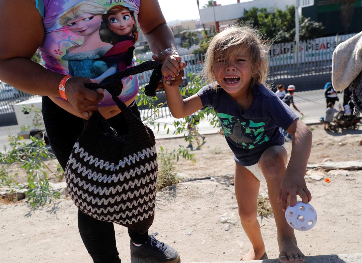 Cheili Nalleli Mejia Meza, a five-year-old migrant girl from Honduras, part of a caravan of thousands from Central America trying to reach the United States, cries as she holds the hand of her mother, Maria Lila Meza Castro after they ran away from tear gas released by U.S. border patrol.