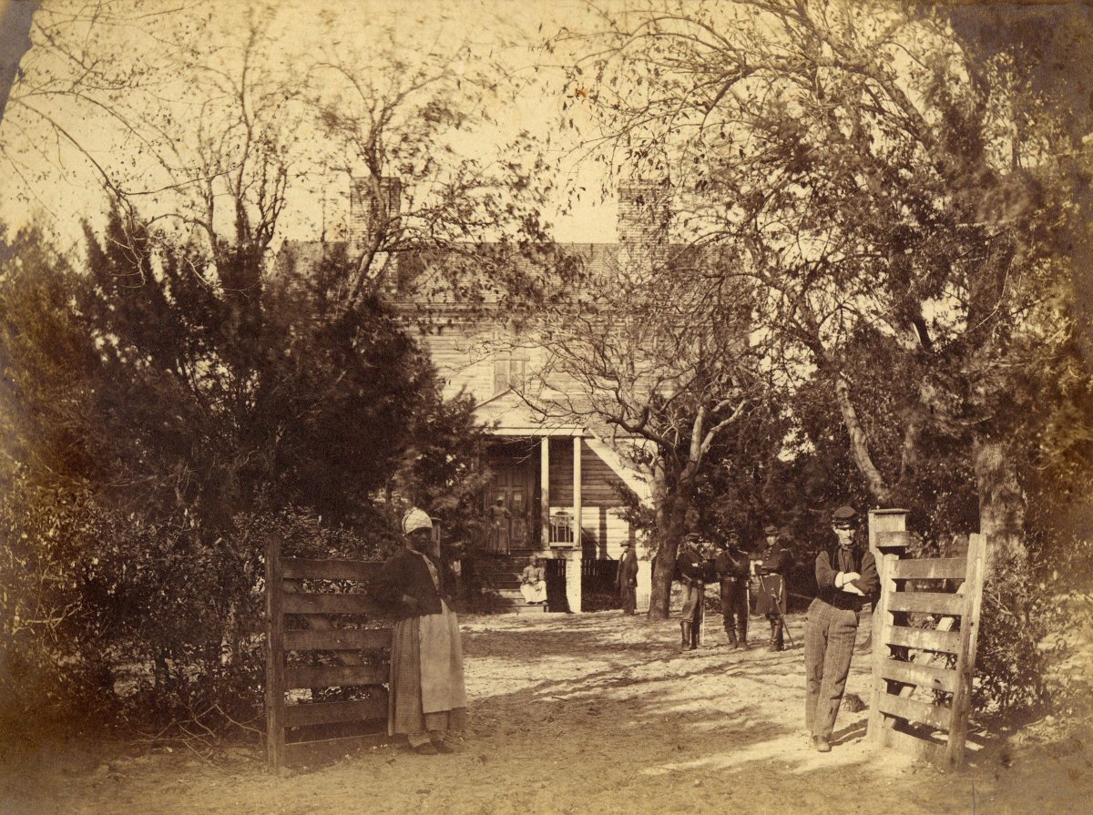 A newly liberated female slave and Union soldiers stand at the entrance to the captured plantation of the General Thomas F. Drayton, Hilton Head Island, South Carolina. 