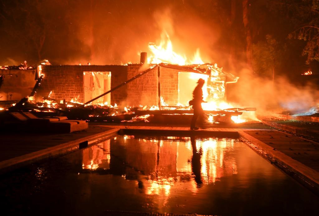A firefighter walks by the a burning home in Malibu, Calif., Friday, Nov. 9, 2018. A Southern California wildfire continues to burn homes as it runs toward the sea.