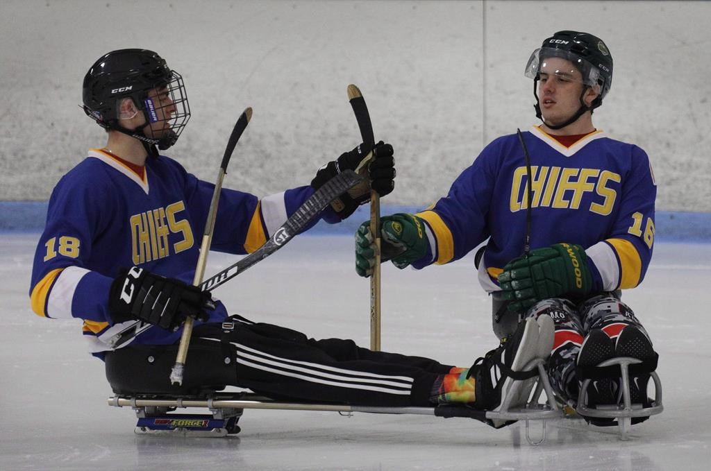 Humboldt Broncos hockey player Jacob Wassermann, left, and teammate Ryan Straschnitzki compare sticks during a sled hockey scrimmage at the Edge Ice Arena in Littleton, Colo., on Friday, Nov. 23, 2018. THE CANADIAN PRESS/Joe Mahoney