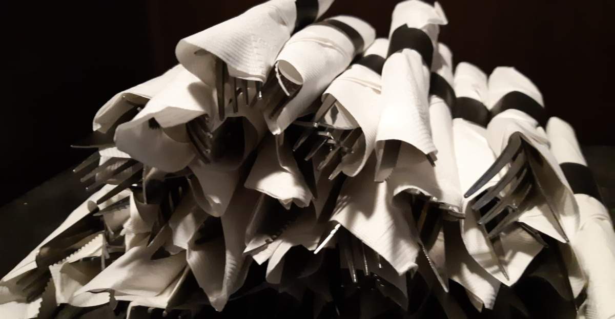 A pile of carefully shined and rolled cutlery.