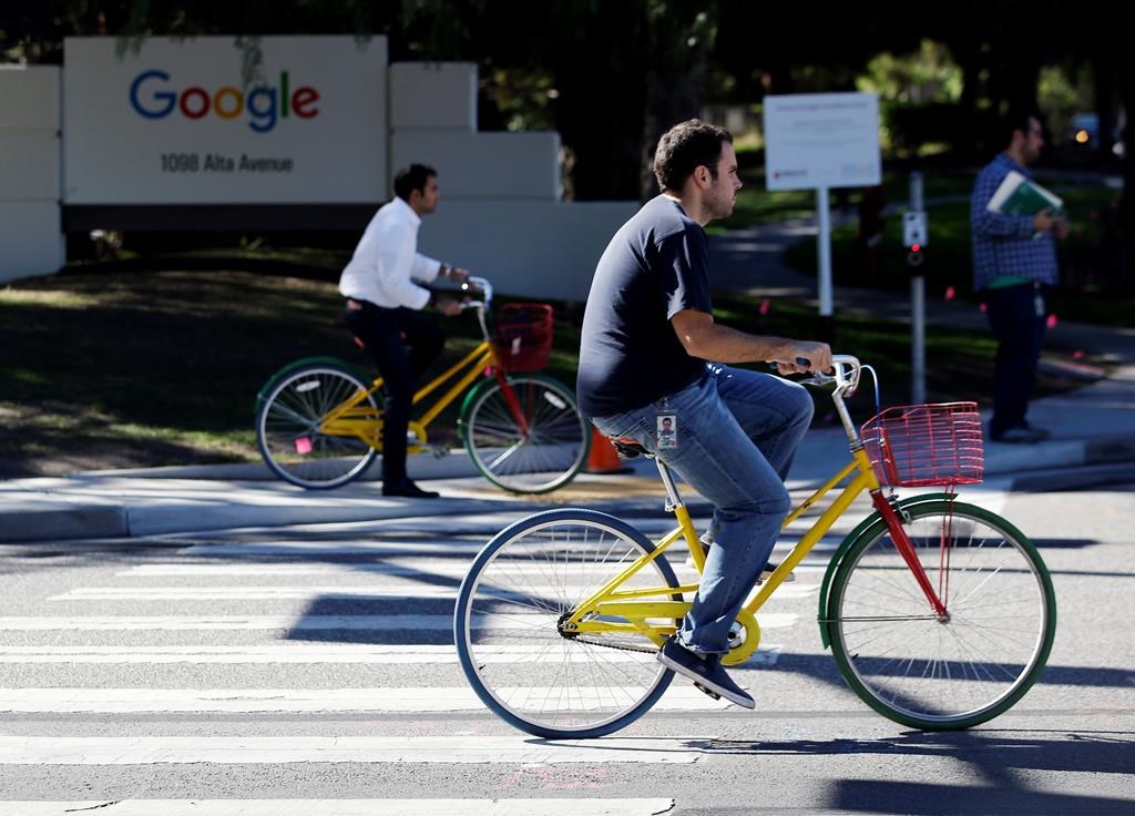 FILE - In this Oct. 20, 2015 file photo, employees ride company bicycles outside Google headquarters in Mountain View, Calif.