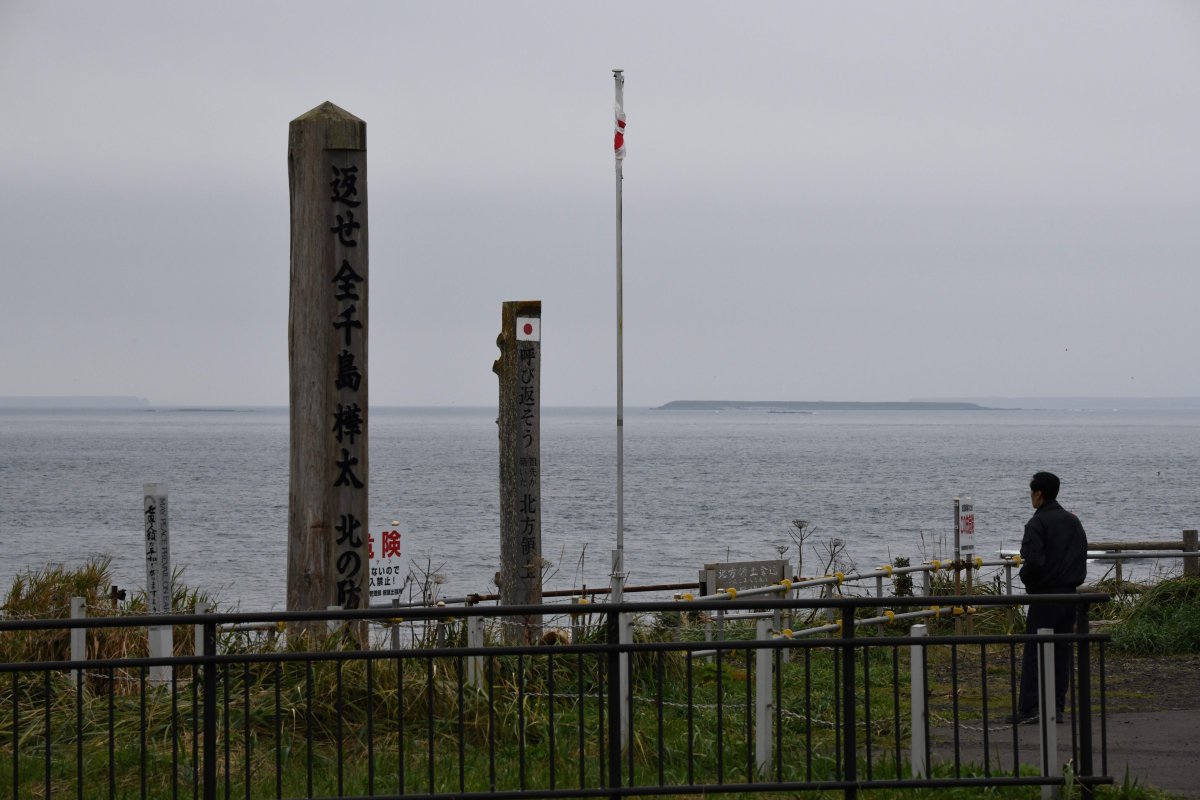 This picture taken on October 11, 2018 shows a tourist visiting Cape Nosappu, a point on the Nemuro peninsula, Hokkaido prefecture as the Habomai Islands are seen in the background. Four of the islands known as the Northern Territories in Japan and the southern Kuril islands in Russia are disputed.
