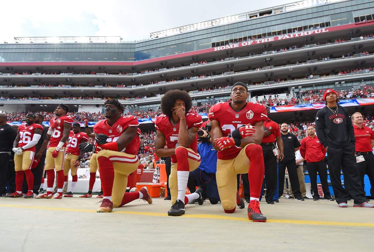 (L-R) Eli Harold, Colin Kaepernick and Eric Reid of the San Francisco 49ers kneel on the sideline during the National Anthem on Oct. 2, 2016, in Santa Clara, Calif.
