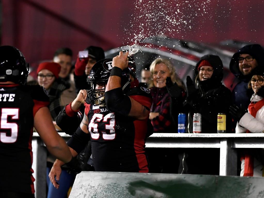 Ottawa Redblacks offensive lineman Jon Gott (63) smashes a beer can on his helmet after chugging it, as he celebrates his team's touchdown against the Toronto Argonauts during second half CFL football action in Ottawa on Friday, Nov. 2, 2018. THE CANADIAN PRESS/Justin Tang.