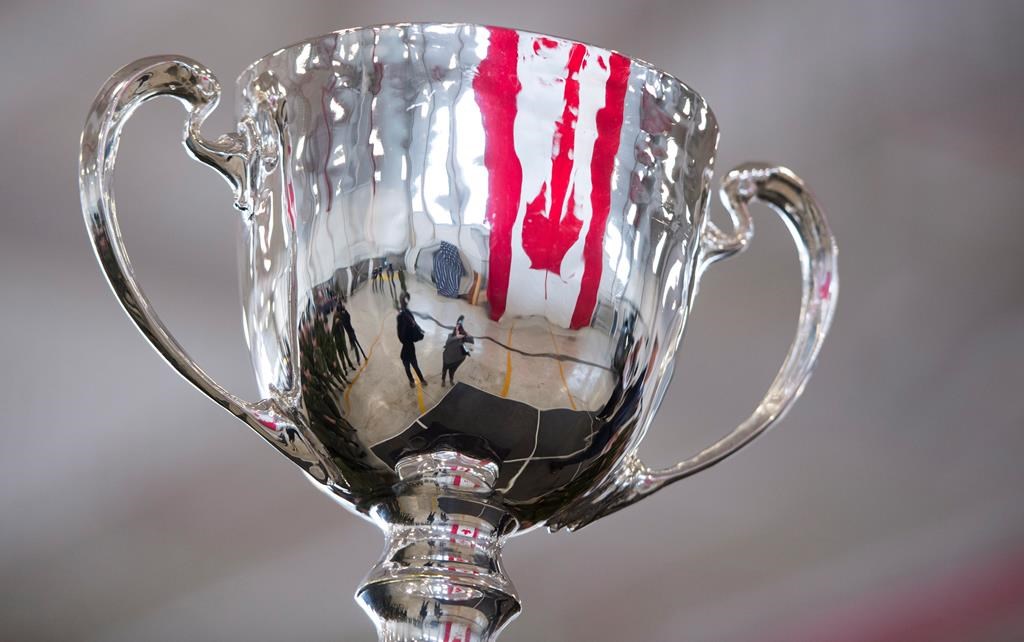 The Canadian flag is reflected in the Grey Cup as it arrives at Canadian Forces Base in Edmonton, Alta., Tuesday, Nov. 20, 2018. The 106th Grey Cup will be played Sunday between the Ottawa Redblacks and the Calgary Stampeders.