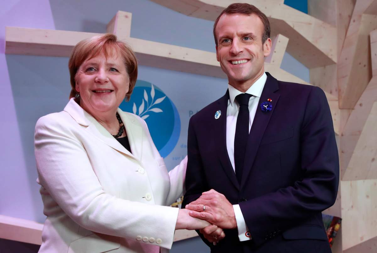 German Chancellor Angela Merkel and French President Emmanuel Macron hold hands after leaving books at the peace library of the Paris Peace Forum as part of the commemoration ceremony for Armistice Day, in Paris, Sunday, Nov. 11, 2018.
