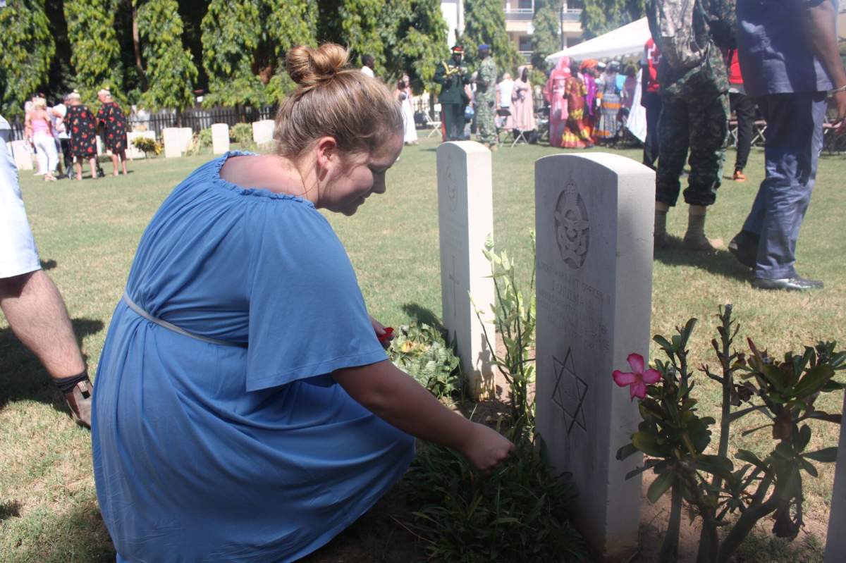 One of the students in Catherine Conrad's geography courses kneels at Warrant Officer Basil Ralph Yorke at the Fajara War Cemetery in the city of Banjul on Nov. 11, 2018.
