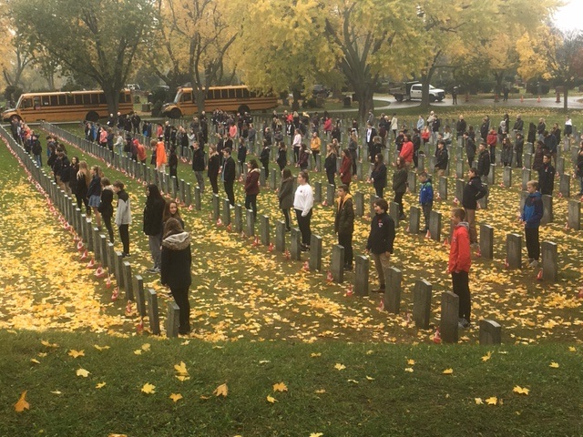 Students from Aldershot School place poppies on the graves of Canadian soldiers as part of the No Stone Left Alone initiative.