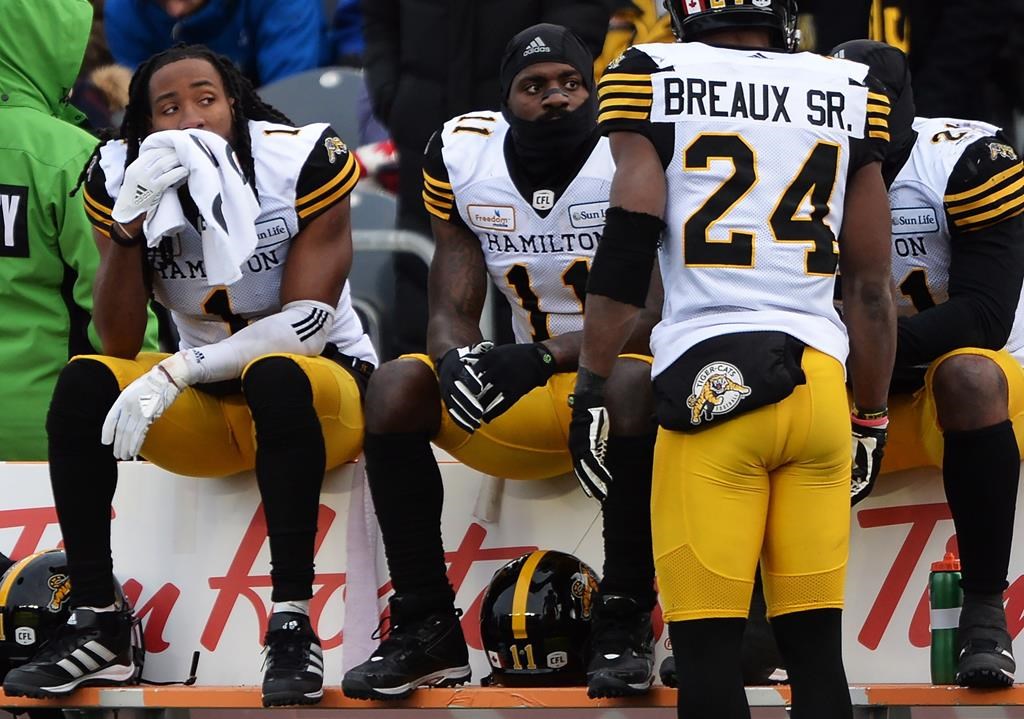 Hamilton Tiger-Cats players Don Unamba (1), Larry Dean (11) and Simoni Lawrence (21) sit on the bench as Delvin Breaux Sr. (24) looks on during second half CFL East Division Final action against the Ottawa Redblacks, in Ottawa on Sunday, Nov. 18, 2018.