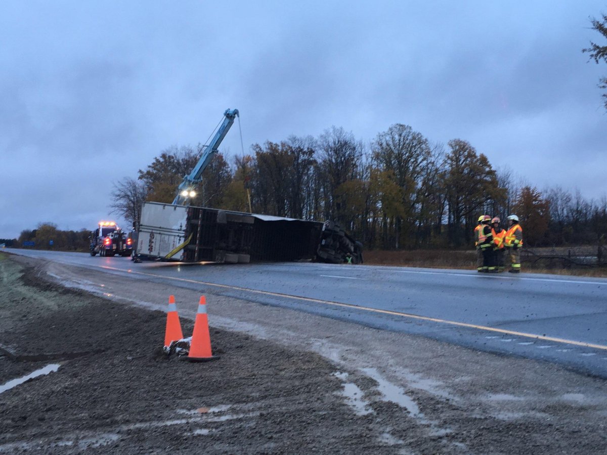 A crane and a tow truck can be seen in this photo, after a big rig tipped on its side heading east on Hwy 401.